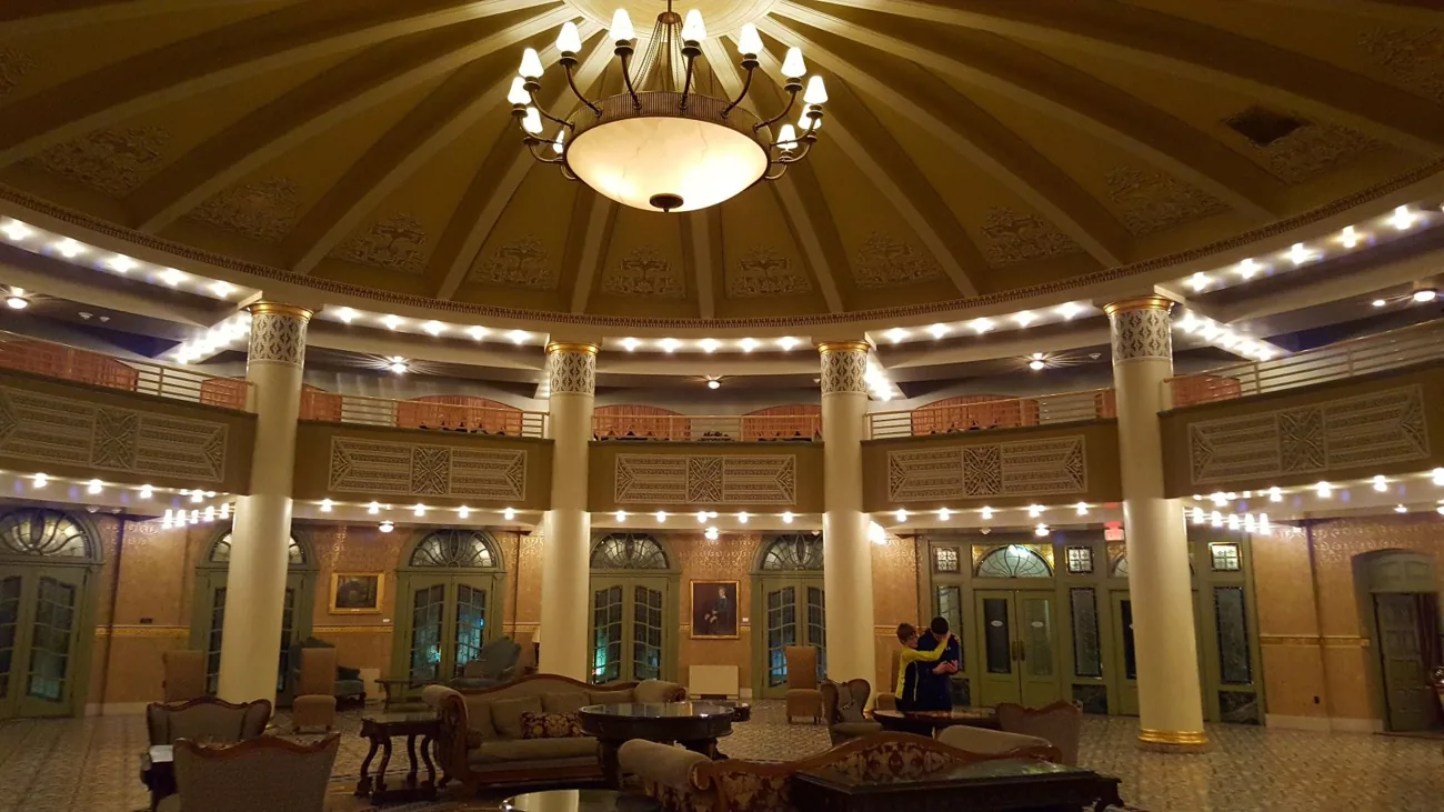 Warmly lit smaller circular lobby with columns, chandeliers, and seating